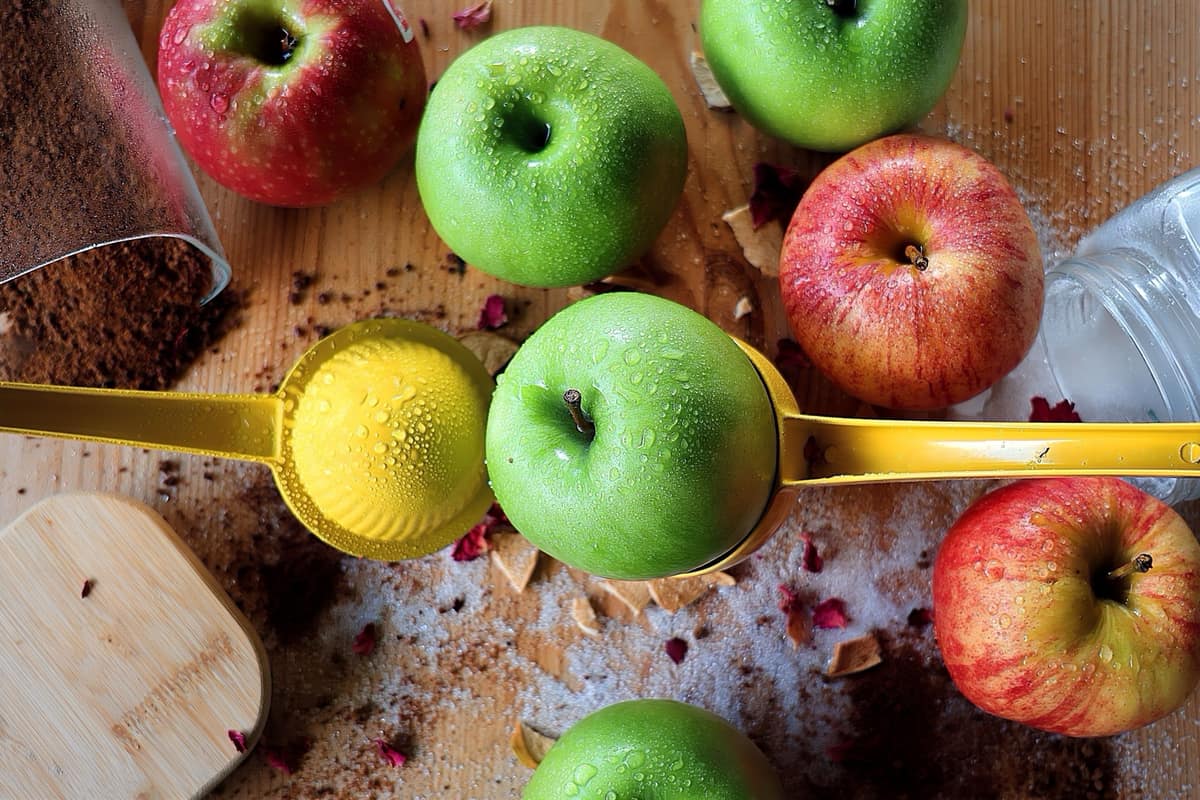 An electric juicer beside apples on a counter