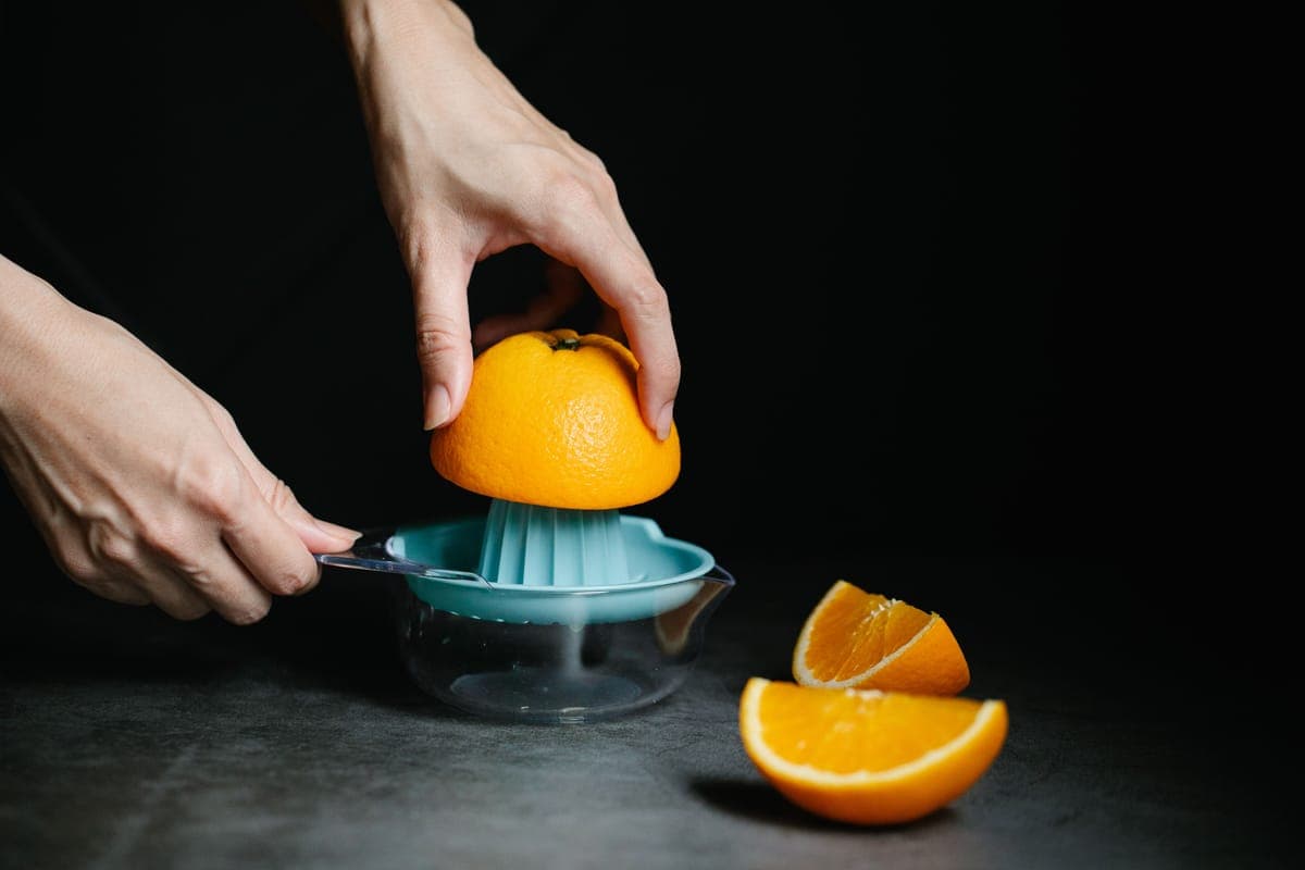 A lever-arm citrus press on a counter with lemons