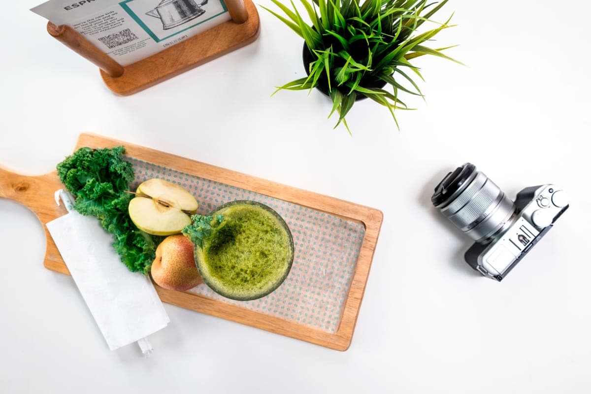 A juicing machine with green vegetables on a counter