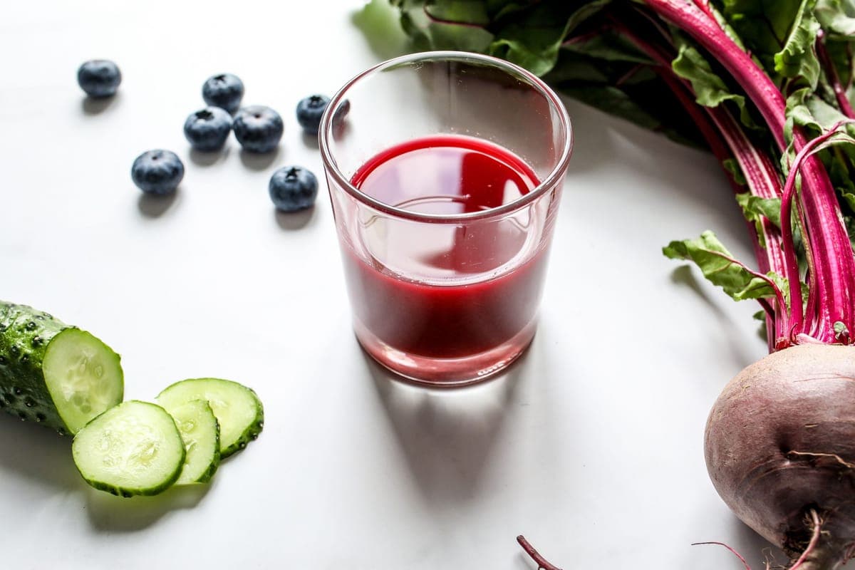 Beetroot juice in a glass beside fresh beets