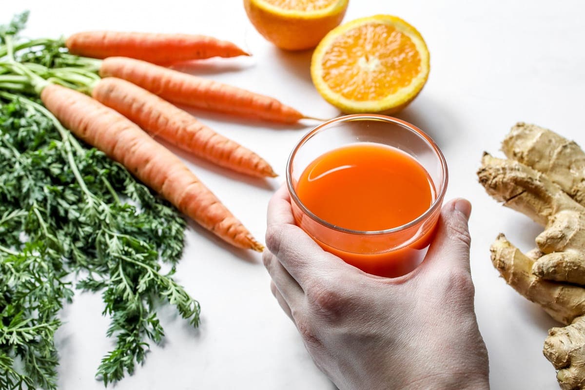 Carrot juice in a glass beside fresh carrots