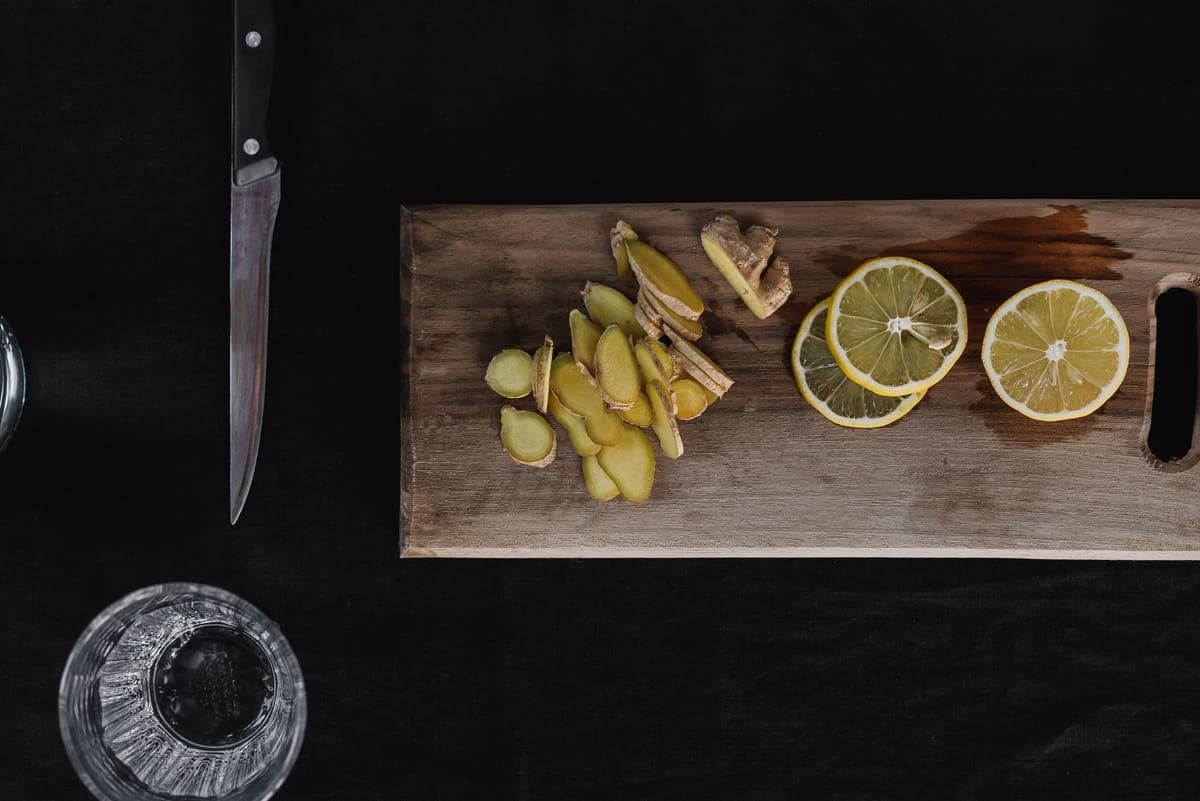 Fresh ginger root and slices on a light surface