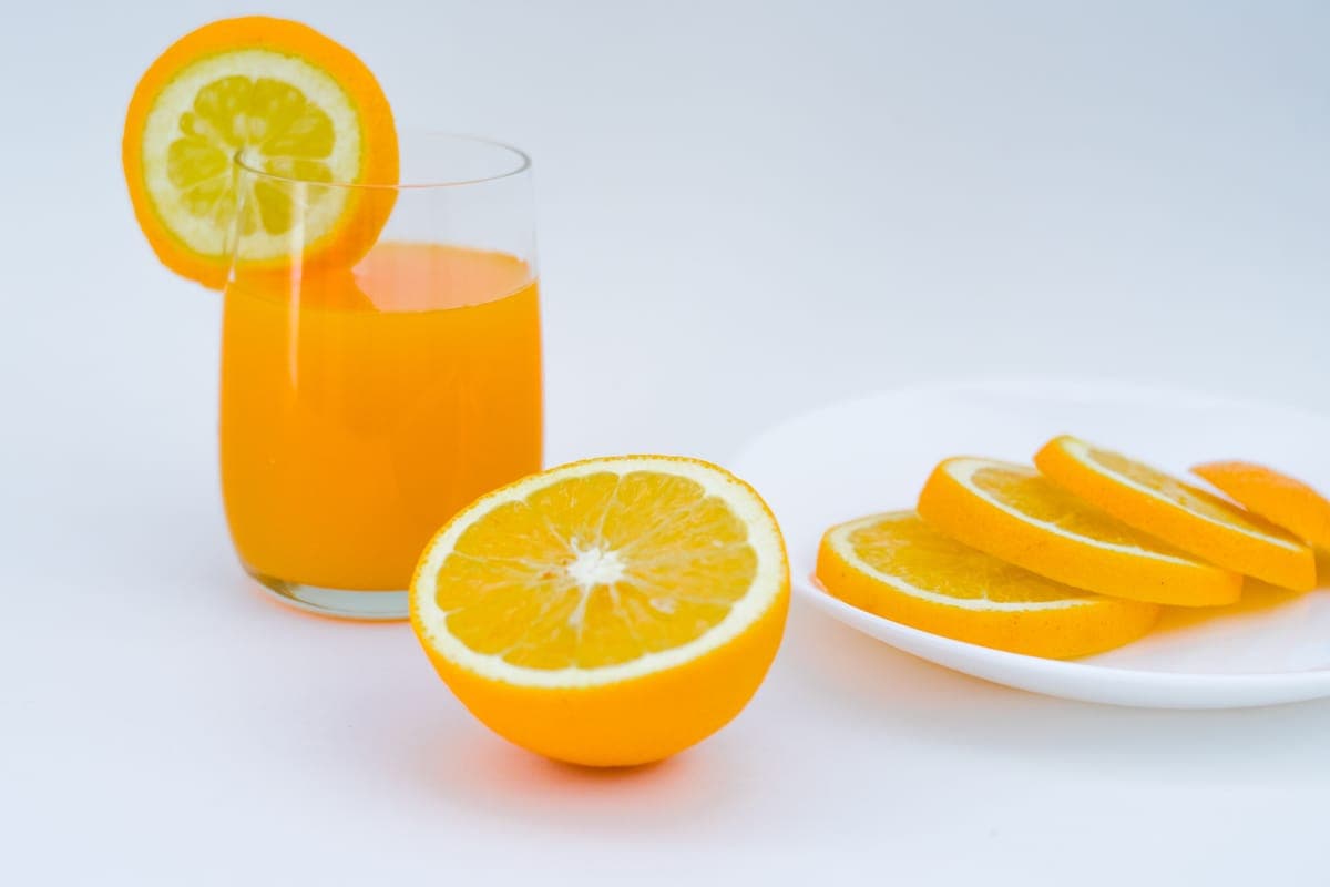Fresh oranges beside a glass of orange juice