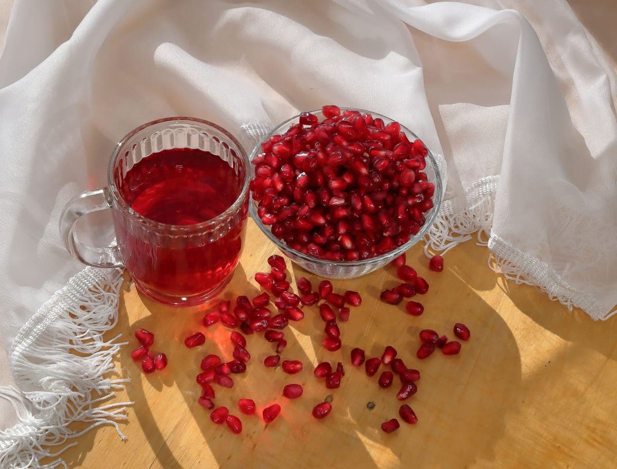 Pomegranate seeds beside a glass of pomegranate juice
