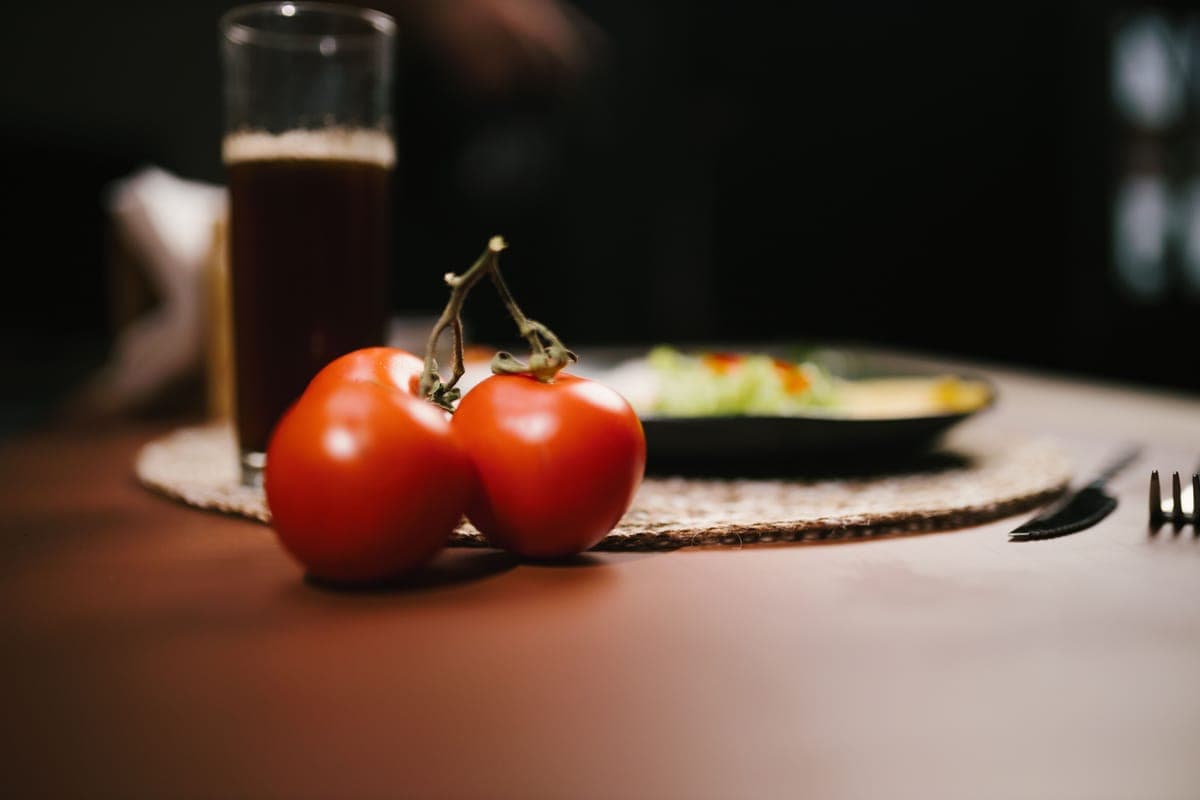 Tomato juice in a glass beside fresh tomatoes