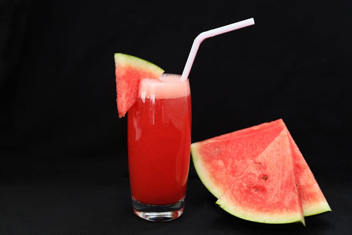 Watermelon slices beside a glass of watermelon juice