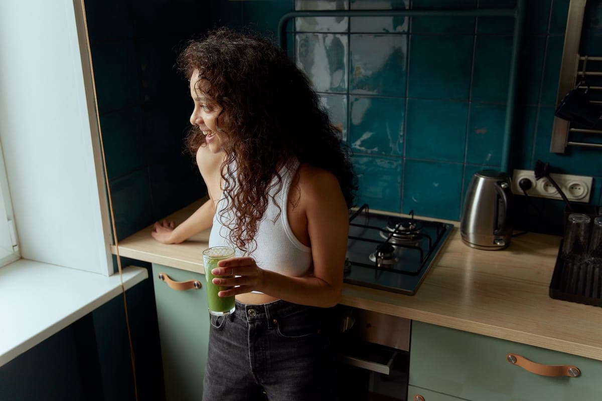 A person drinking green juice in a bright kitchen