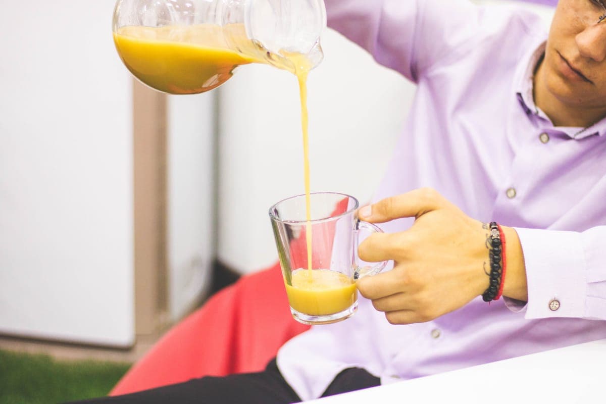 Juice being poured into a glass on a light counter
